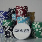 Pilhas de fichas de pôquer coloridas ao lado de um botão de dealer sobre mesa lisa