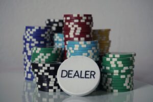 Pilhas de fichas de pôquer coloridas ao lado de um botão de dealer sobre mesa lisa