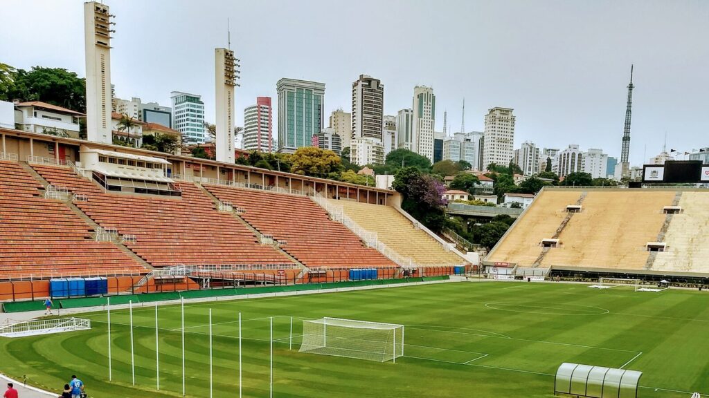 Arquibancadas e gramado do Estádio do Pacaembu, em São Paulo, com o horizonte da cidade ao fundo