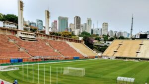 Arquibancadas e gramado do Estádio do Pacaembu, em São Paulo, com o horizonte da cidade ao fundo