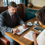 Executivos em reuniao de negocios discutindo documentos, imagem ilustrativa de governanca corporativa