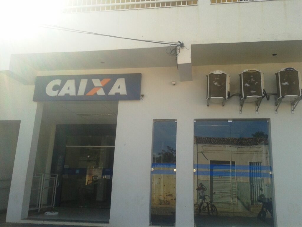 Fachada de agência da Caixa Econômica Federal com letreiro azul da marca Caixa
