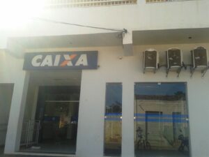 Fachada de agência da Caixa Econômica Federal com letreiro azul da marca Caixa