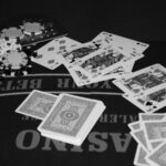 Fichas de poker e cartas sobre mesa de cassino, foto ilustrativa em preto e branco