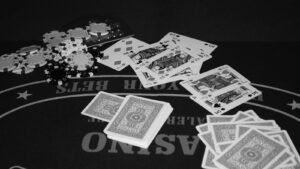 Fichas de poker e cartas sobre mesa de cassino, foto ilustrativa em preto e branco