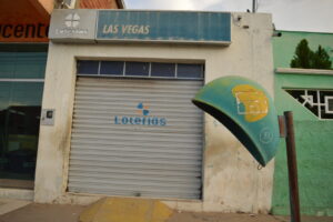 Fachada de casa lotérica com a marca oficial Loterias Caixa, porta fechada