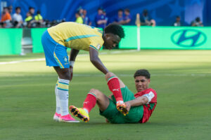 Vinícius Júnior, de amarelo, ajuda adversário marroquino caído em campo durante partida da Copa do Mundo de 2026