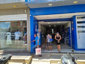 Fachada de agência das Loterias Caixa com clientes na entrada