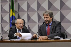 Deputado Pedro Uczai (PT-SC) ao microfone ao lado do senador José Pimentel em reunião de comissão mista no Congresso Nacional, 2016 (Foto de arquivo: deputado Pedro Uczai em reunião de comissão no Congresso, 2016 (não é do PL 1808/2026).)