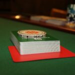 Baralho com botão de dealer sobre mesa de pôquer com fichas ao fundo