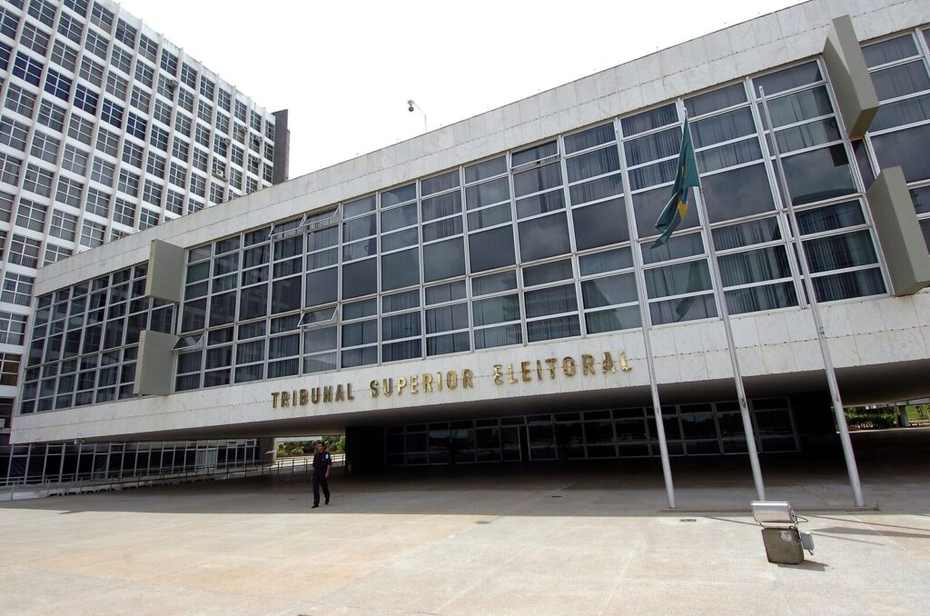 Fachada do prédio do Tribunal Superior Eleitoral (TSE) em Brasília, com a placa 'Tribunal Superior Eleitoral' visível e bandeira do Brasil. (Foto de arquivo: sede do Tribunal Superior Eleitoral, em Brasília.)
