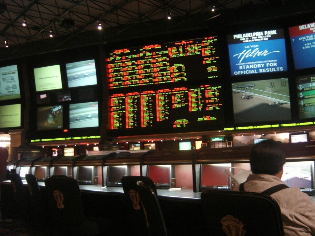 Sportsbook do Hilton com dezenas de telas exibindo eventos esportivos e linhas de apostas, ambiente de casa de apostas físico (Foto de arquivo: sportsbook do Hilton (2006), imagem ilustrativa sobre exibição de odds, sem relação com um evento específico.)