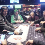 Mesa final de torneio de pôquer com jogadores, fichas e cartas sobre feltro, com telões ao fundo (Foto de arquivo: mesa de torneio de pôquer (World Poker Tour), sem relação direta com o evento BSOP Millions.)