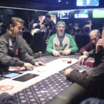 Partida de pôquer com jogadores ao redor de uma mesa verde, fichas e cartas visíveis (Foto de arquivo: partida de pôquer genérica, sem relação direta com o torneio BSOP Millions.)