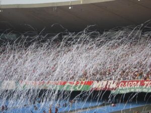 Arquibancada do Maracanã tomada por torcedores do Fluminense em meio a serpentinas brancas, com faixa tricolor ao fundo (Foto de arquivo: torcida do Fluminense no Maracanã, sem relação com jogo específico.)