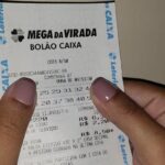 Comprovante de aposta da Mega-Sena da Virada nas mãos de um apostador (Foto ilustrativa: comprovante de aposta da Mega-Sena da Virada, 2020.)
